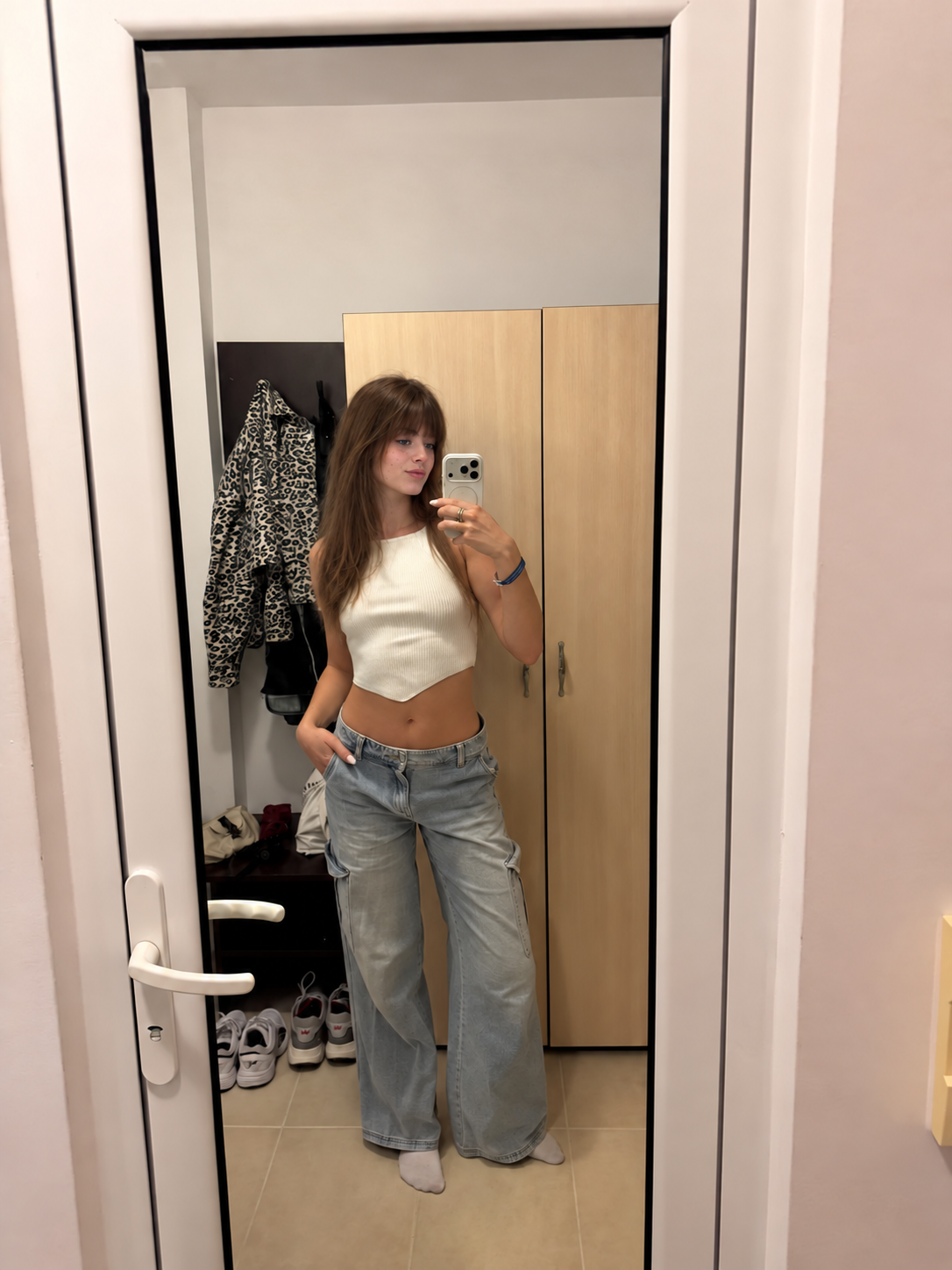 Hannah taking a mirror photo in a cream top and jeans